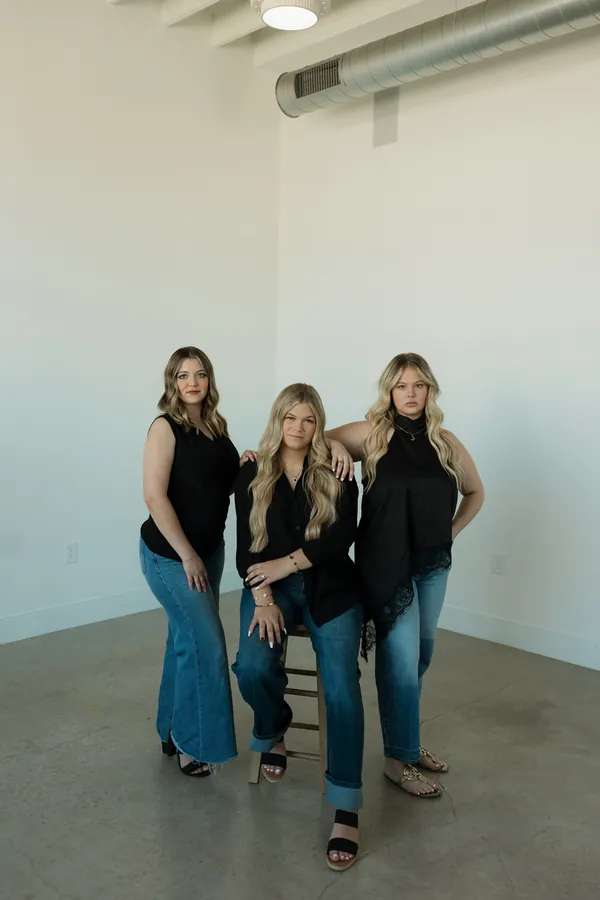 Three stylists posing together in the salon studio